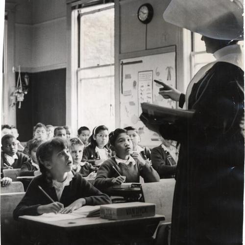 [Teacher instructing a class at St. Patrick's Grammar School]