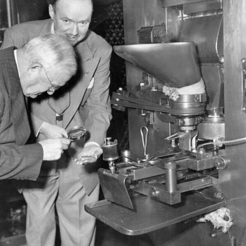 [Two unidentified people inspecting freshly minted coins at the U. S. Mint in San Francisco]