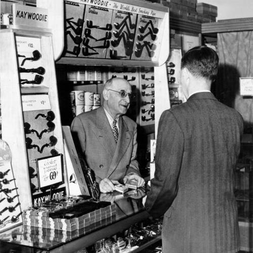 [Henry Green standing behind the tobacco counter at Weinstein Company department store at 1041 Market Street]