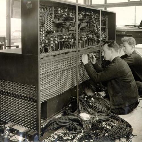 [Workers installing a control board for San Francisco-Oakland Bay Bridge electric railway system]