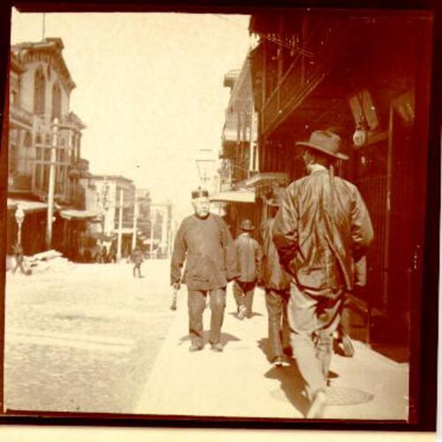 [Men walking on a sidewalk in Chinatown]