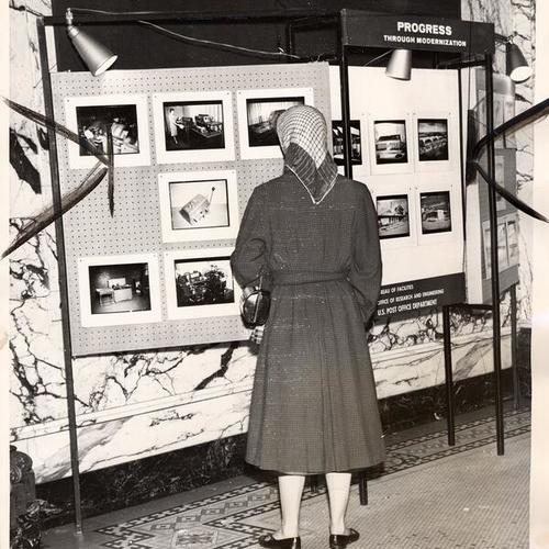 [Woman looking at the photos that reflect the modernization work done at Seventh and Mission Post Office]