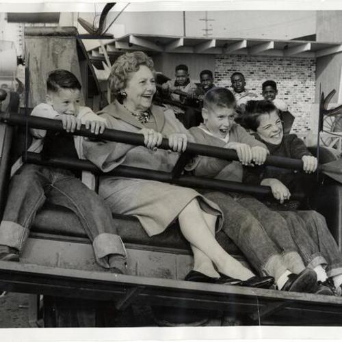 [Eva C. Whitney and three boys on a ride at Playland at the Beach]