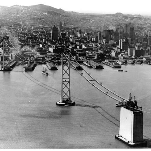 [Aerial view of San Francisco span of Bay Bridge center anchorage and towers with city of San Francisco visible in background]