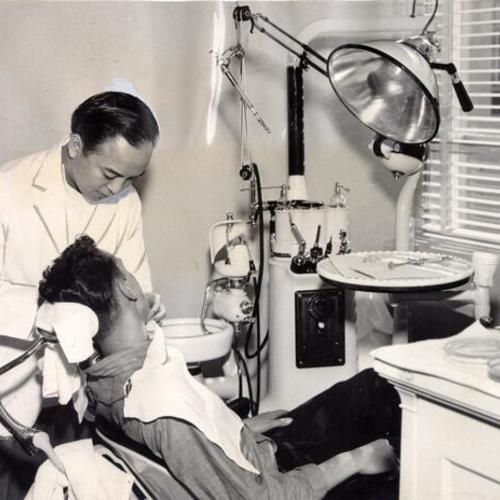 [Dr. Fred Hong examining the teeth of a boy at the Youth Guidance Center]