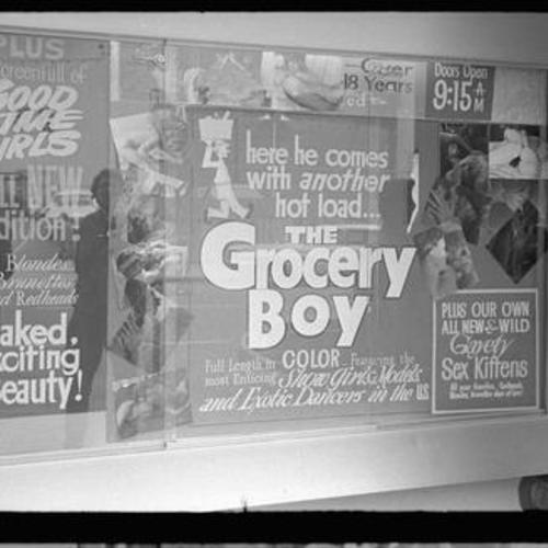 Exterior view of Gayety Theatre window display with movie posters and photo collage of people in sexual poses