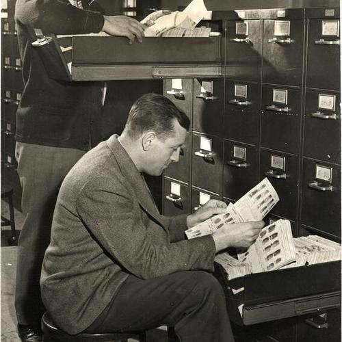 [Officers Martin Bell and George Crofton looking through fingerprint files in the Police Department's Bureau of Identification]
