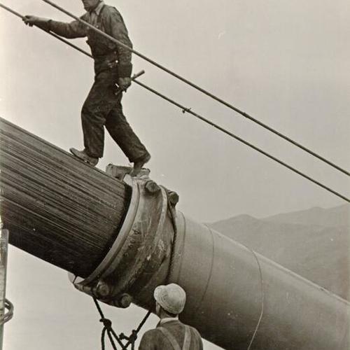 [Construction worker walking up cable on the Golden Gate Bridge]