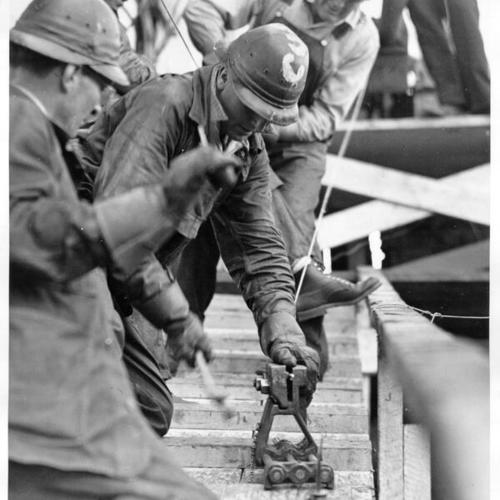 [Construction workers finishing cable work on the Golden Gate Bridge]