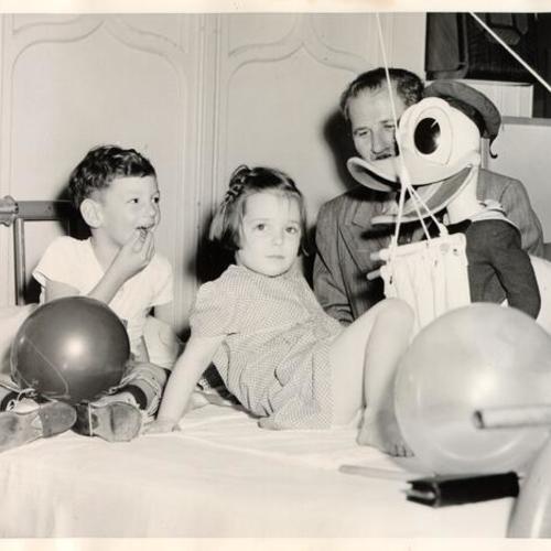 [Man with a Donald Duck doll visiting patients at the Shriners' Hospital for Crippled Children]