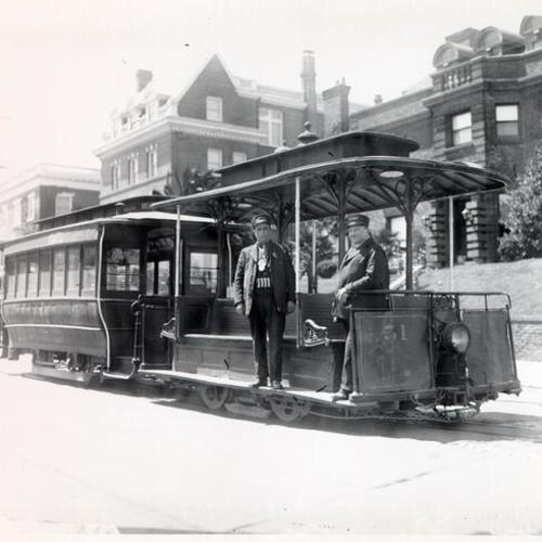 [Two cable car operators standing on a cable car at Pacific Avenue and Divisadero Street]