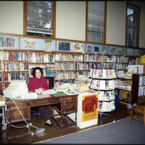[Children's Room reference desk staffed by Carol S. at the Noe Valley Branch of the San Francisco Public Library]