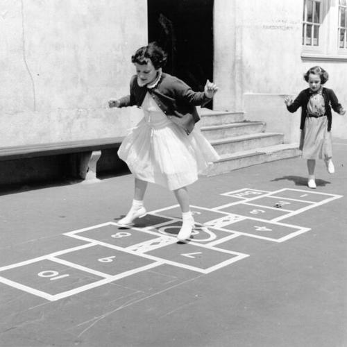 [Two children playing hopscotch in the playground at Gough School for the Deaf at 1945 Washington Street]