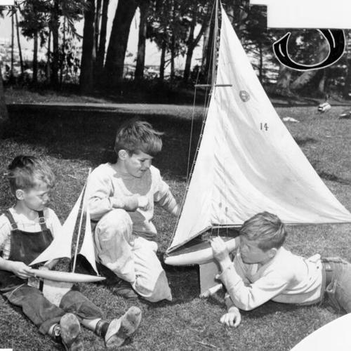 [Three children with model sailboats near Spreckels Lake in Golden Gate Park]