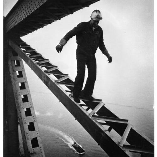 [Construction worker on the San Francisco-Oakland Bay Bridge balanced on a narrow steel structure]