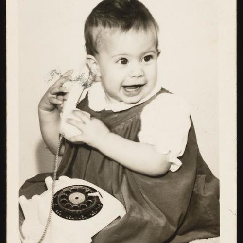 Portrait of infant holding telephone