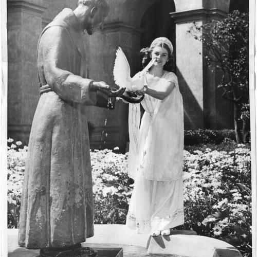 [Cora Babcock, dressed as the Goddess of Peace, posing next to a statue of Saint Francis]