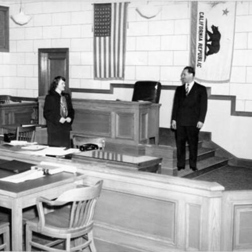 [Two people standing in a courtroom in City Hall]