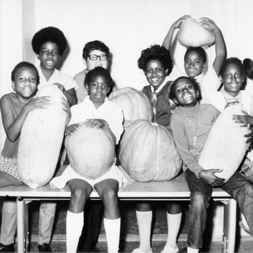 [Group of students from Bret Harte Elementary School posing with large pumpkins and squash]
