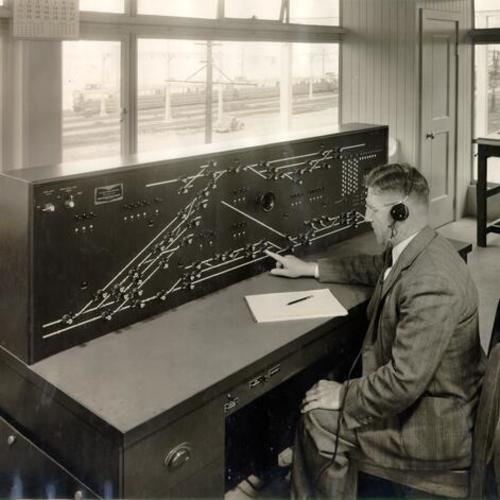 [Engineer Ross Davis sitting at a control board for San Francisco-Oakland Bay Bridge electric trains]