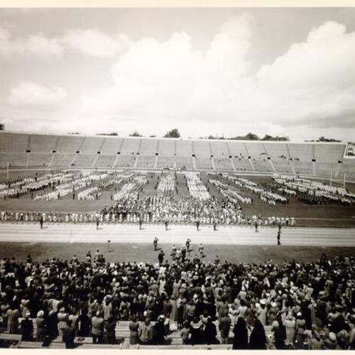 [Crowd of people watching a marching band at Kezar Stadium]
