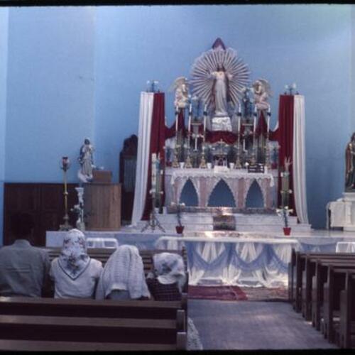 View of church altar and people kneeling