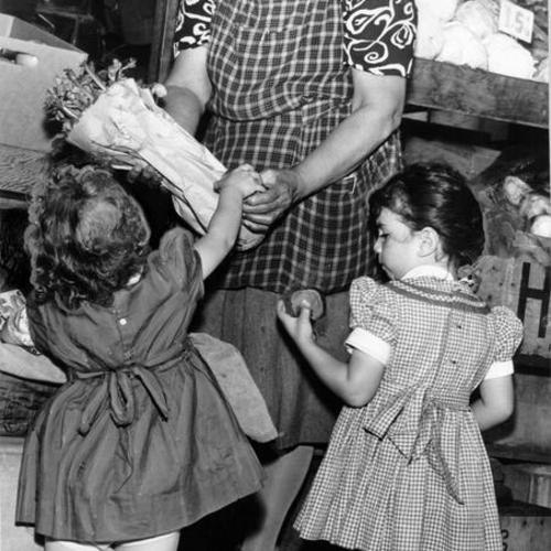 [Mrs. M. Moskito selling vegetable to two children at the Farmers' Market on Alemany Boulevard]