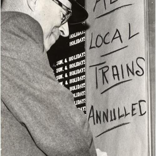 [Southern Pacific assistant stationmaster A. W. Serel writing a sign to notify commuters about lack of train service during strike]