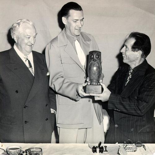 [Senator Pat McCarran of Nevada watching as artist Beniamino Bufano presents Vernon Willis, president of the Las Vegas Press Club, with a sculpture of an owl]