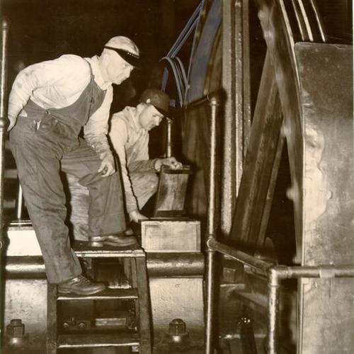 [J. T. Crowe and W. T. Malchow examining a broken cable at a cable car powerhouse]