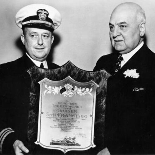 [Two unidentified men holding a plaque honoring the men of the cruiser U.S.S. San Francisco]