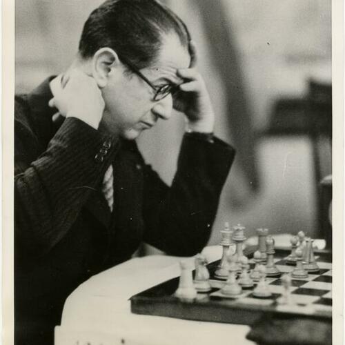 Chess champion Jose Capablanca with one hand on his forehead and other on his collar during chest match