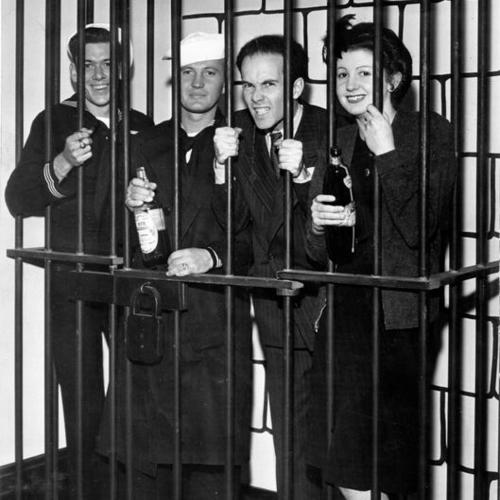 [Group of people posing in a fake prison cell labeled "Alcatraz"]
