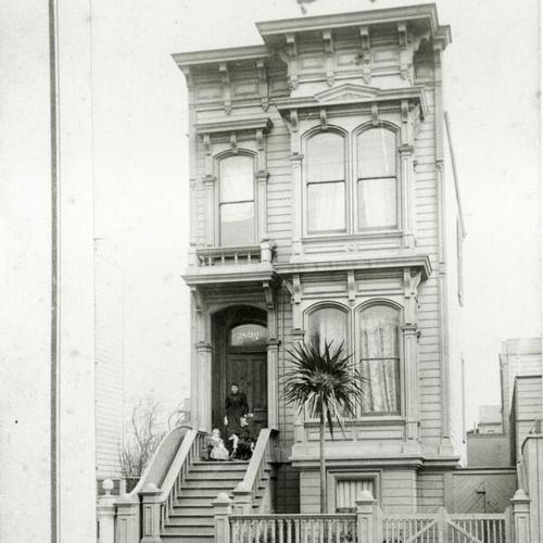 [Portrait of a woman and two children posing in front of house on Howard Street]