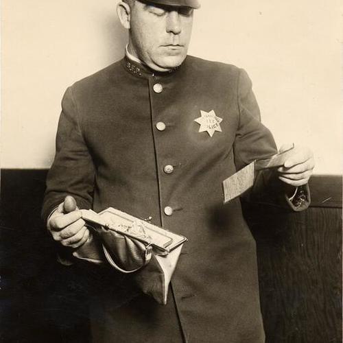 [Officer Jack McGreevy holding a woman's purse on his right hand, and an ID on his left hand]