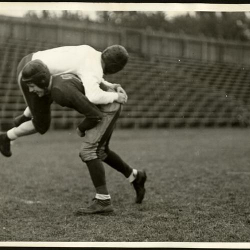 [John McDonagh, of St. Ignatius High School football team, carrying quarterback Roy Pinelli over his shoulder]
