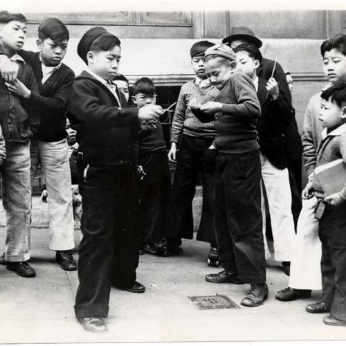 [Group of boys playing with fire crackers in Chinatown on New Year's]
