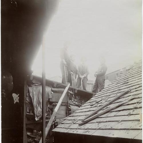 051 People with axes standing on top of wooden building during demolition
