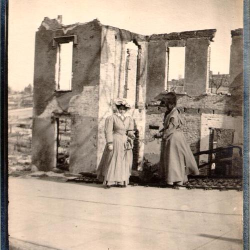 [Two women standing near the ruins of a building at Green and Gough streets]
