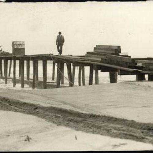 [Unidentified worker walking on pier near Fleishhacker Pool]