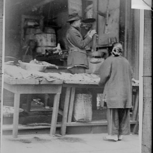 [Fish market; man with scales, woman customer]