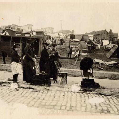 [People cooking on the street near a refugee camp]