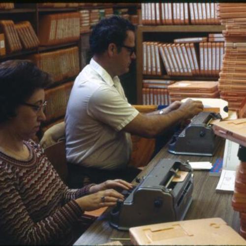 [A woman and a man creating braille materials]
