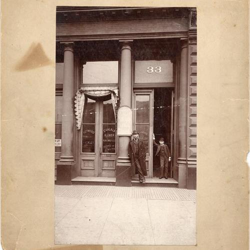 [Frank Heywood and Frank Trower standing in front the offices of Heywood & Hackley at 33 Steuart Street]