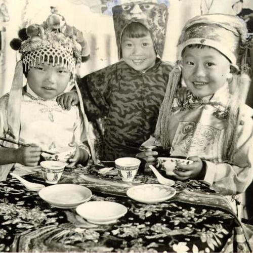[Three children sitting down for a meal during, Moon Festival]