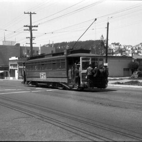 [Ocean Avenue near Miramar looking northwest at crowded outbound #12 car 136 with students riding fender]