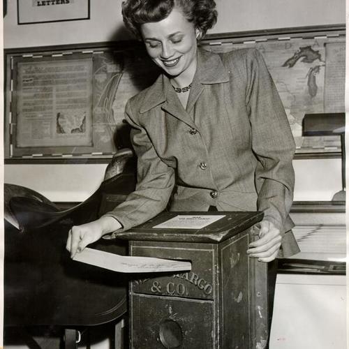 [Miss Roberta Hilliard placing a letter in an old Wells Fargo mail box]