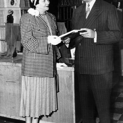 [Ivan A. Anixter assisting Rita Ferbeck in the hosiery department at the Weinstein Company department store at 1041 Market Street]