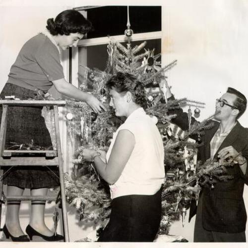 [Members of the Catholic Alumni Club trimming a Christmas tree at Clarendon Hall in Laguna Honda Home]