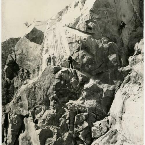 Workers rappelling down rock face during O’Shaughnessy Dam construction